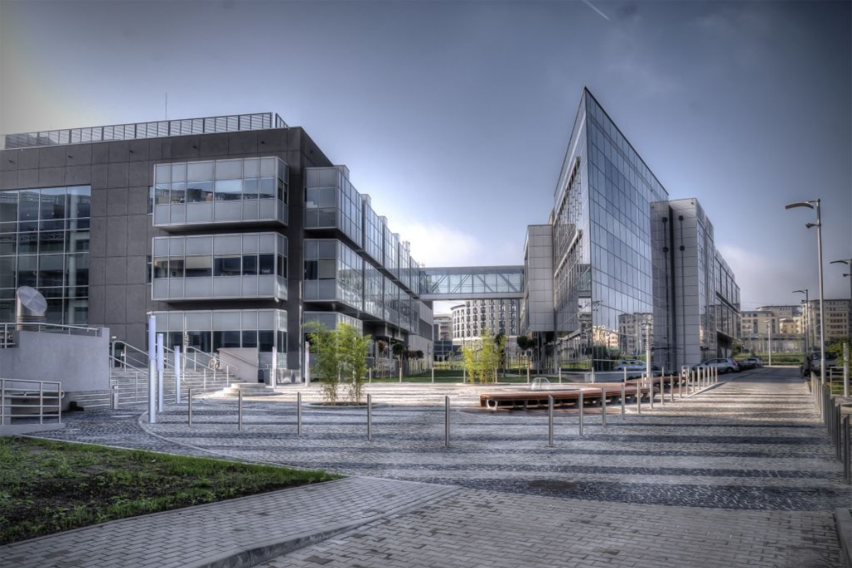 Nowoczesny kompleks biurowy z przeszklonymi budynkami połączonymi kładką