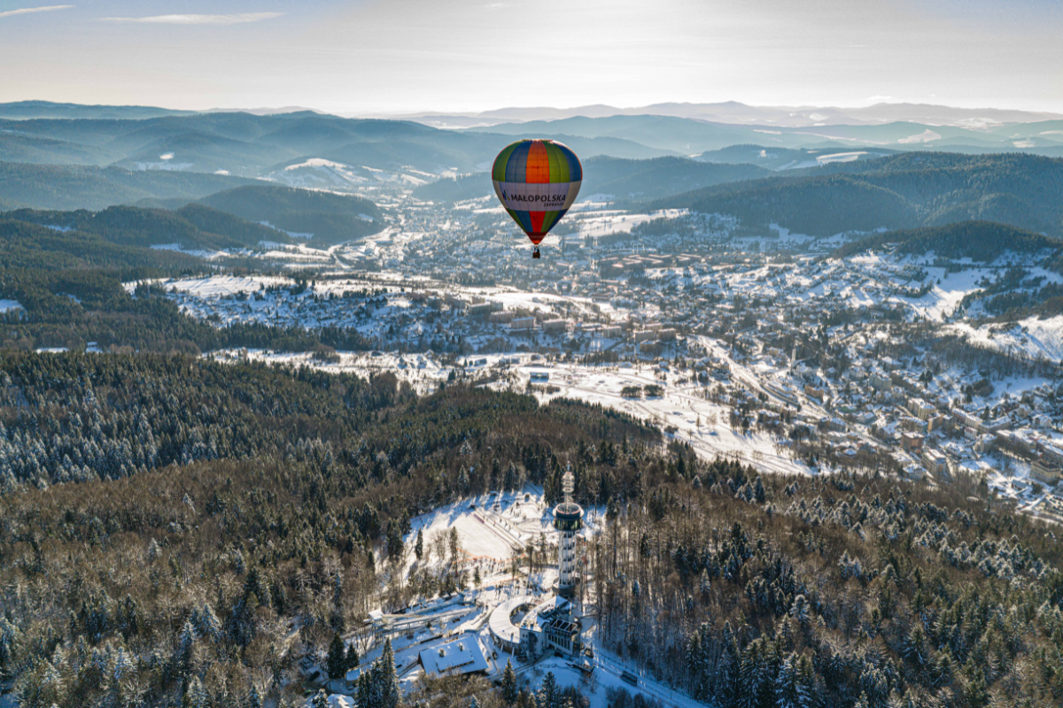 kolorowy balon z napisem Małopolska unoszący się w powietrzu nad ośnieżonym górzystym krajobrazem 